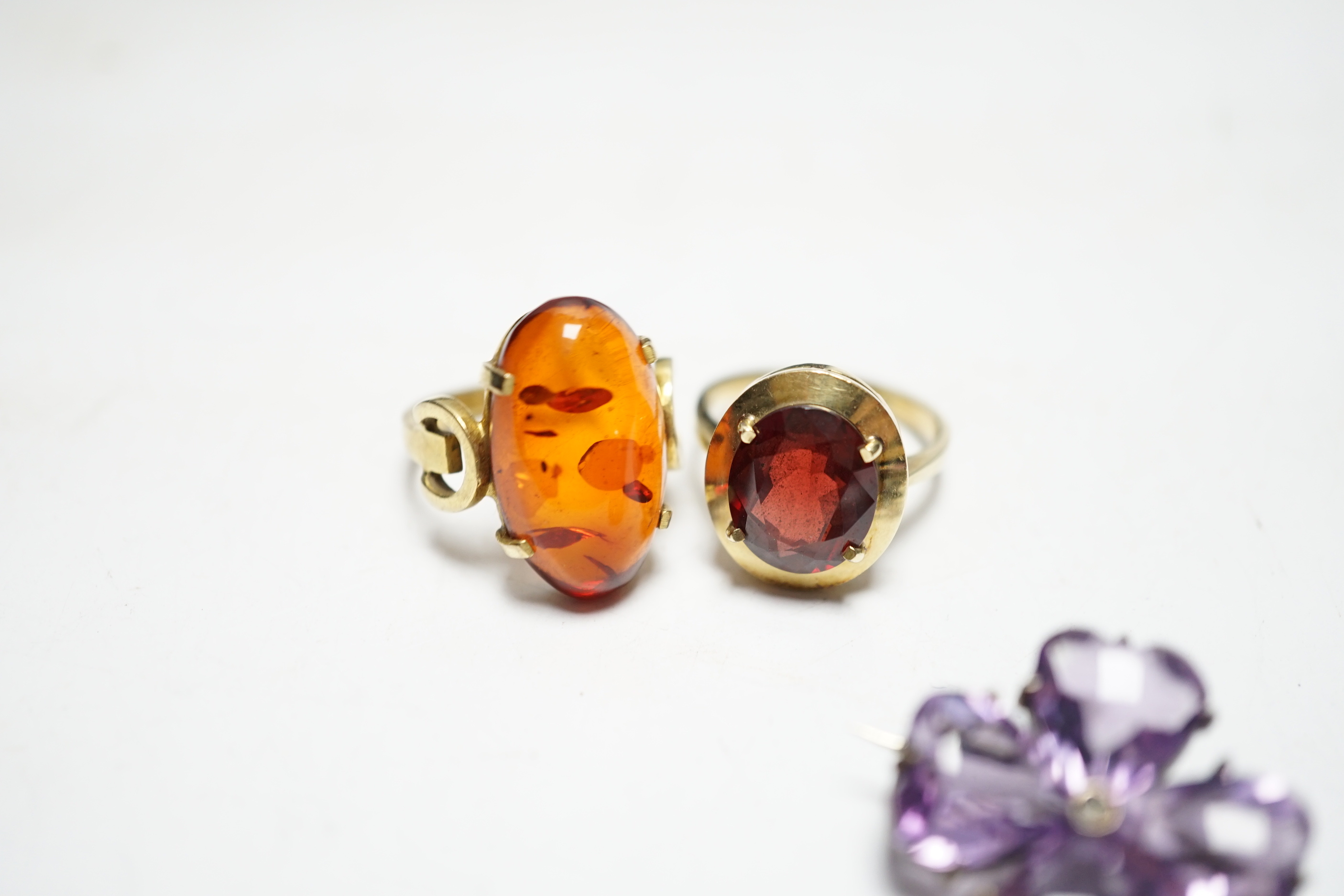 A 333 yellow metal and amber set ring, a 585 and gem set ring and an amethyst and seed pearl set white metal brooch.